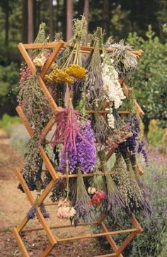 a wooden rack with dried flowers hanging from it's sides on a dirt road