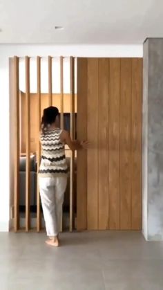 a woman standing next to a black pole in a room with white walls and flooring