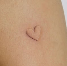 a small heart tattoo on the back of a woman's thigh, with no bra