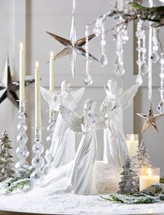 an angel figurine sitting on top of a table surrounded by candles and christmas decorations