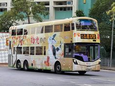 a double decker bus driving down the street in front of a tall building with chinese characters painted on it