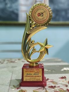 a gold trophy with a star on top and a clock in the middle is sitting on a table