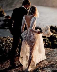 a man and woman standing next to each other on top of a hill near the ocean