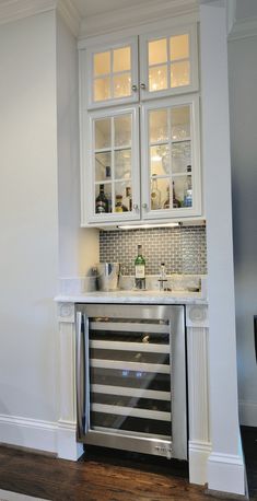 a kitchen with white cabinetry and stainless steel appliance in the corner, along with hardwood flooring