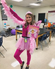 a girl in pink is holding up a book