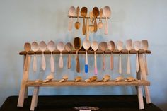 wooden spoons are lined up on a shelf in front of a wall mounted rack