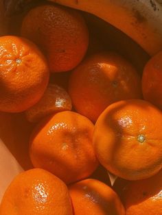 a bunch of oranges sitting in a bowl next to a banana on top of a table