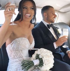 a bride and groom sitting in the back seat of a car holding champagne flutes with their hands