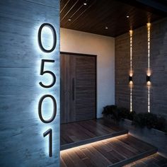 the numbers are lit up in front of a modern door and entrance to a house