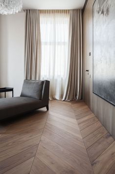 a living room with wood flooring and large window covered in drapes next to a couch