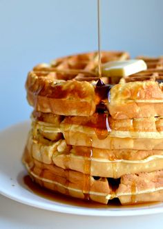 a stack of waffles with syrup being drizzled on top