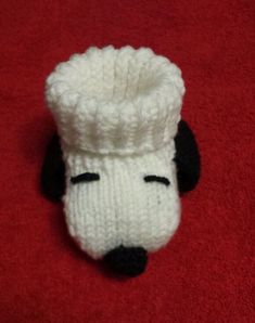 a knitted dog with a hat on it's head sitting on a red surface