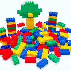 a pile of colorful lego blocks sitting on top of a white table next to a tree