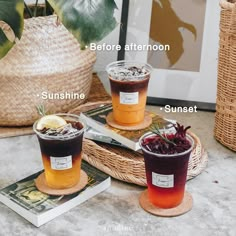 three drinks sitting on top of a table next to a basket filled with books and plants