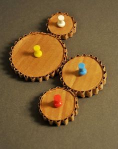 three wooden bottle caps with different colored knobs on the top one is empty and two are not