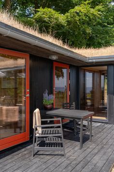 a table and chairs on a wooden deck with grass growing on top of the roof