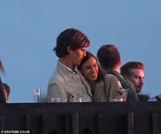 two people are sitting next to each other on a balcony with drinks in their hands