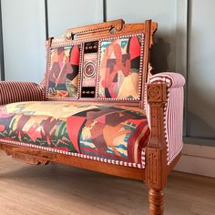 an old fashioned wooden couch with colorful fabric on it's armrests and back