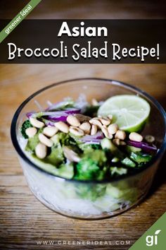 a salad with broccoli, onions and lemon wedges in a glass bowl