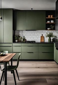 a kitchen with dark green cabinets and wooden table in front of the stove top oven