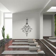 a room with yoga mats and plants on the floor, in front of a white wall