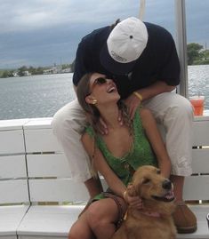 a man and woman are sitting on a bench with a dog in front of them