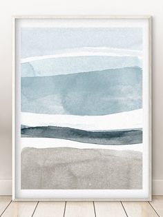 an abstract watercolor painting with blue and gray colors on the wall in a white frame