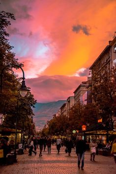 people are walking down the street at sunset