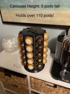 there is a coffee maker on the counter next to some cups and balls in front of a sign that says carousel height 5 pods tall holds over 10 pods