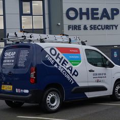 a blue and white van parked in front of a fire and security building with the words oheap on it