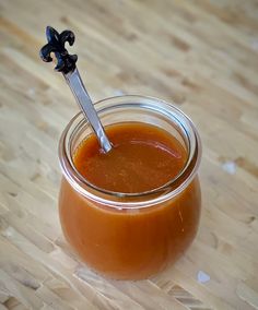 a jar filled with liquid sitting on top of a wooden table next to a spoon