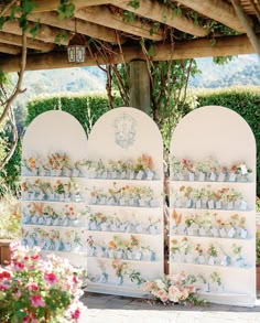 an outdoor ceremony area with floral decorations and flowers on the wall, along with seating for guests