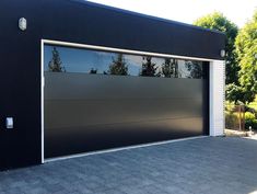 a black garage door with windows reflecting trees