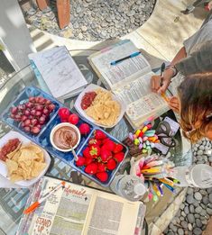 a table topped with lots of food next to an open book on top of a glass table