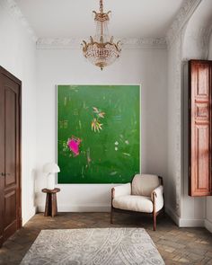 a living room with a large painting on the wall and a chair in front of it