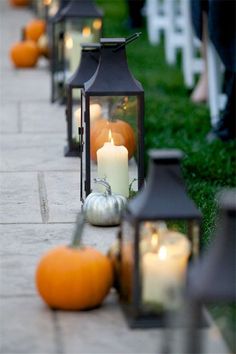 a line of lanterns with pumpkins and candles on the ground next to each other