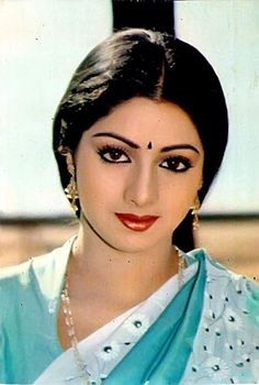 an old photo of a woman in blue and white sari with pearls on her head