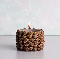 a candle that is made out of pine cones and has a lit flame in the middle