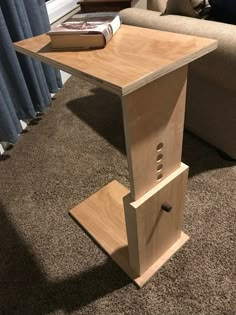 a small wooden table sitting on top of a carpeted floor next to a couch