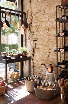 a wine cellar filled with lots of bottles and baskets next to a wall full of hanging utensils