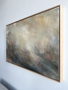 a large painting hanging on the wall above a couch in a room with white walls