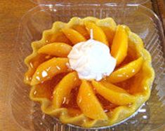 an orange pie with whipped cream on top in a glass dish sitting on a wooden table