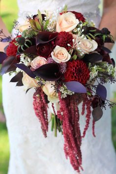 a bridal holding a bouquet of red and white flowers