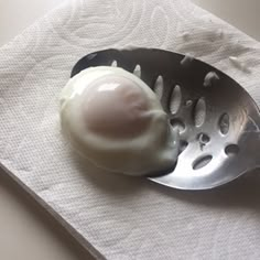 an egg in a grater sitting on top of a white napkin next to a fork