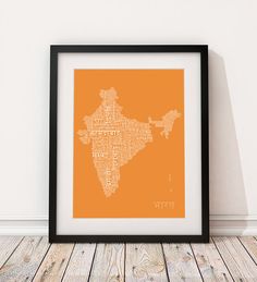 an orange and black framed map of india with the capital cities in white, on a wooden floor