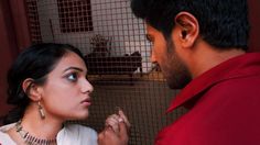 a man and woman standing next to each other in front of a caged area