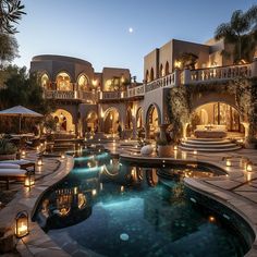 an outdoor swimming pool surrounded by lights and patio furniture in front of a large house