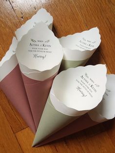 four folded paper cones sitting on top of a wooden table next to an envelope with writing