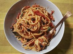 a white bowl filled with pasta and sauce on top of a tablecloth covered table