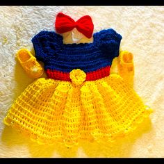 a crocheted snow princess dress with a red bow on the top and yellow skirt